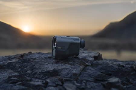 Garmin action camera resting on rugged rocks at sunset with a blurred mountain backdrop for the garm xero l60i rangefinder review.