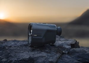 Garmin action camera resting on rugged rocks at sunset with a blurred mountain backdrop for the garm xero l60i rangefinder review.