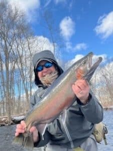 Stuart Wright holding a large steelhead while fishing in cold weather on the Salmon River.